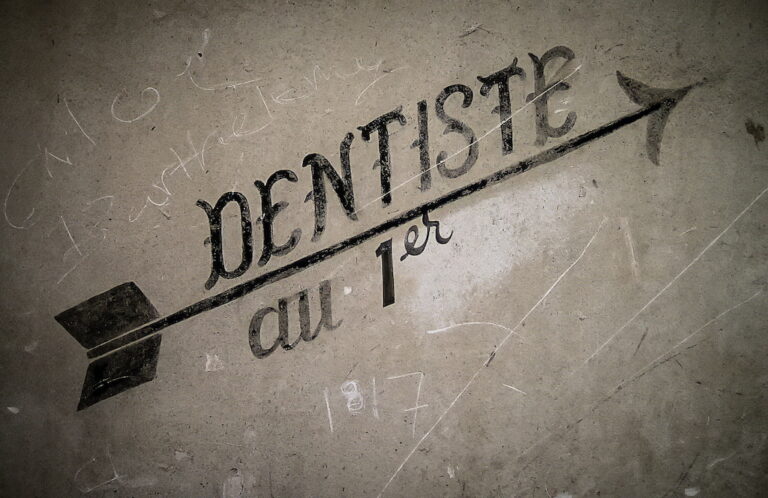 Une enseigne peinte de dentiste et quelques graffitis